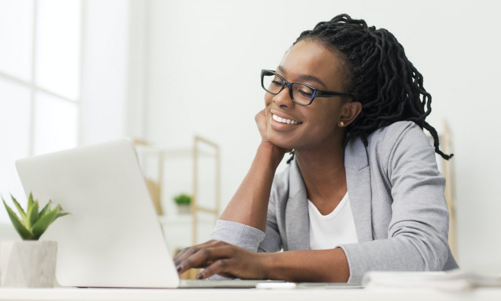 Cheerful Afro Office Girl Using Laptop At Workplace